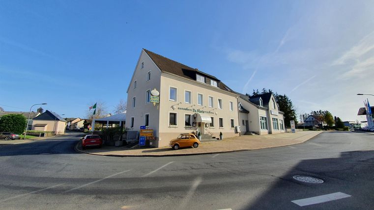 A modern building at a street corner with a clear sky in the background. Some cars are parked on the street.