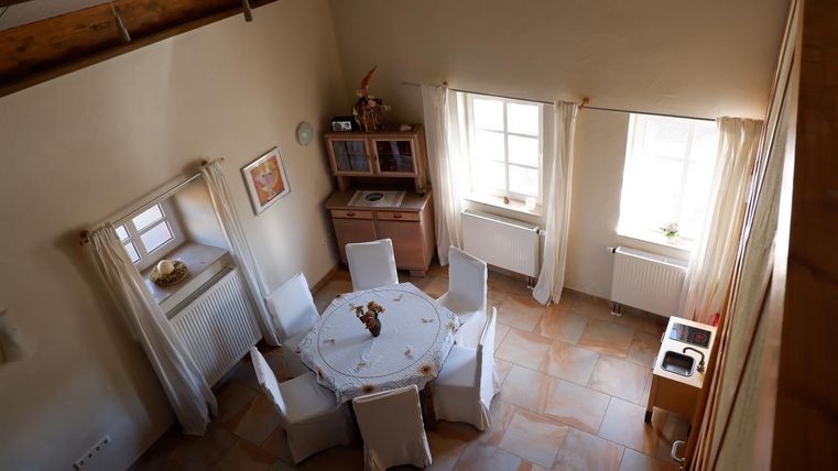 Ein gemütlicher Essbereich mit einem runden Tisch und weißen Stühlen. Helle Fenster lassen viel Licht hinein und schaffen eine einladende Atmosphäre.