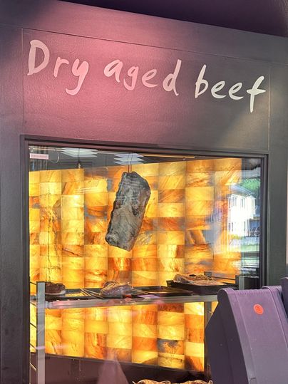 Ein Regal mit trocken gereiftem Rindfleisch. Im Hintergrund leuchtet eine warmartige Wand, die das Fleisch hervorhebt.