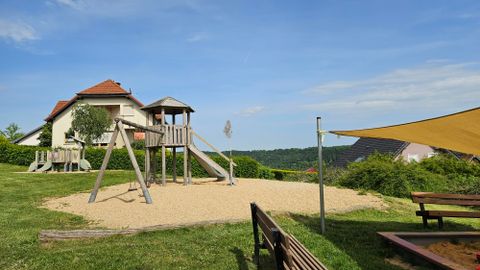 Sandspielplatz mit Holz-Kinderspieltürmen und großem Sandkasten mit Sonnensegel.