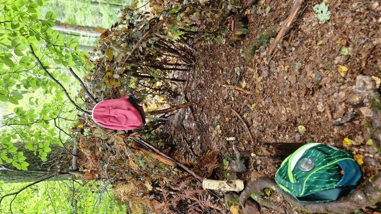Eine Gruppe von Kindern steht im Kreis und schaut aufmerksam auf den Boden. Sie tragen verschiedene Hüte und untersuchen etwas im Erdreich.