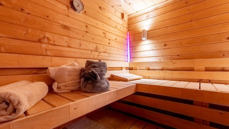 Eine gemütliche Sauna mit Holzverkleidung. Auf den Bänken liegen Handtücher und eine entspannende Atmosphäre herrscht.