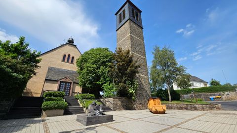 Een mooie plek met een kerk en een hoge toren. Omgeven door bomen en een heldere lucht.