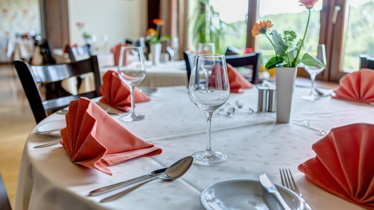 Ein eleganter Restauranttisch mit eleganter Tischdeko. Rote Servietten und Weingläser sind liebevoll arrangiert.