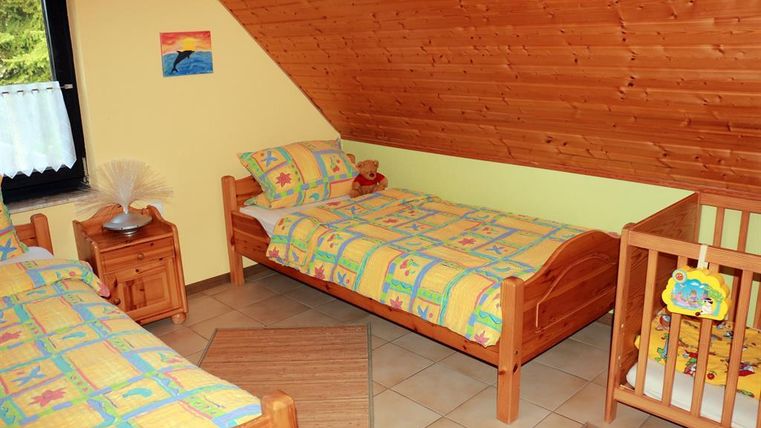 Ein gemütliches Kinderzimmer mit zwei Betten und einem Kinderbett. Die Wände sind in sanften Farben gestrichen und die Bettwäsche hat ein buntes, fröhliches Muster.