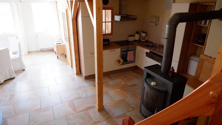 Eine gemütliche Küche mit Holzregalen und einem modernen Ofen. Der Raum hat helle Fliesen und große Fenster für viel Tageslicht.