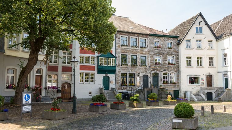 Historische Gebäude in Kornelimünster mit Kopfsteinpflaster und Blumen.
