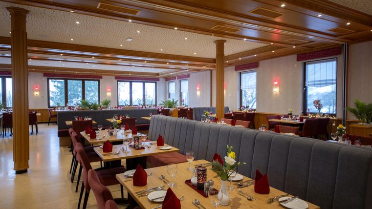 Ein elegantes Restaurant mit einem modernen Innenraum. Tischdecken sind gedeckt und die Fenster bieten einen Blick ins Freie.