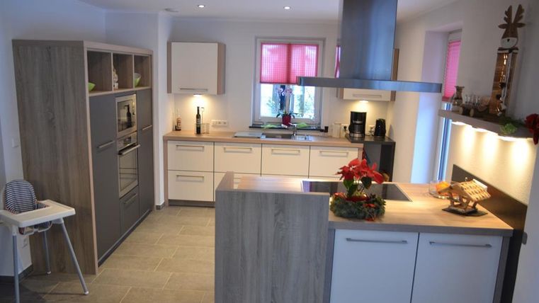 Eine moderne Küche mit Holzregalen und modernen Geräten. Helle Farben und eine gemütliche Atmosphäre schaffen einen einladenden Raum.