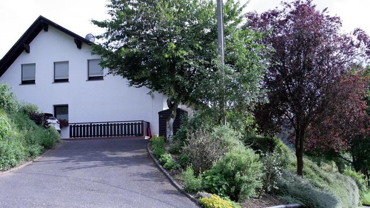 Ein schönes Haus mit einem gepflasterten Weg und üppigem Grün umgeben. Bäume und Sträucher verleihen der Umgebung eine ruhige Atmosphäre.