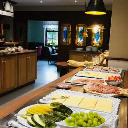 Ein reichhaltiges Frühstücksbuffet mit frischem Obst, verschiedenen Käsesorten und Wurst. Der Tisch ist schön dekoriert und lädt zum Schlemmen ein.