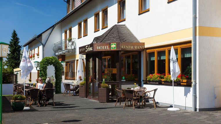 Ein einladendes Hotel mit Restaurant und gemütlicher Terrasse. Die Außenansicht ist hell und freundlich, perfekt für Gäste.