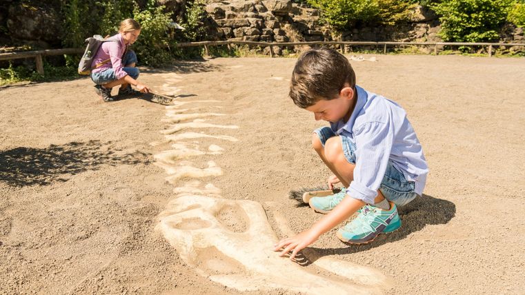 Deux enfants jouent dans un champ de sable. Un garçon dessine quelque chose dans le sable, tandis qu'une fille regarde en arrière.
