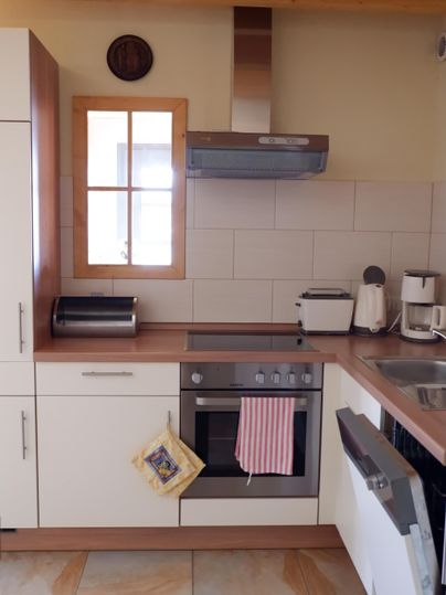 Eine moderne Küche mit Holz- und weißen Schränken. Sie ist ausgestattet mit einem Herd, einer Spüle und Küchengeräten.