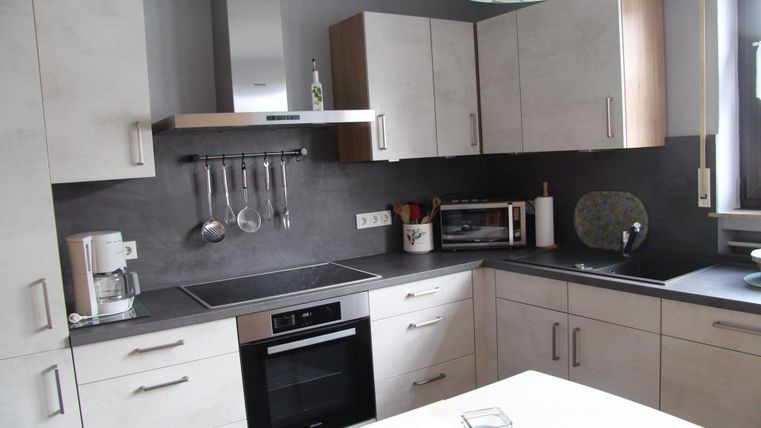 Eine moderne Küche mit hellen Schränken und einer eleganten Arbeitsfläche. Sie ist gut ausgestattet mit einem Herd, einer Mikrowelle und Kochutensilien.