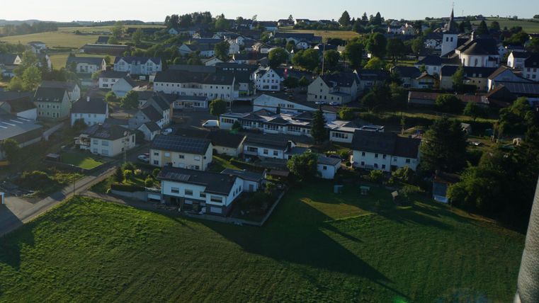 Ein Blick auf ein malerisches Dorf mit zahlreichen Häusern und grünen Wiesen. Die Umgebung ist ruhig und ländlich geprägt.