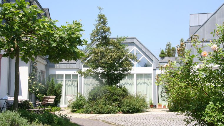 Ein schöner Innenhof mit modernen Gebäuden und viel Grün. Die Bäume und Sträucher schaffen eine einladende Atmosphäre.