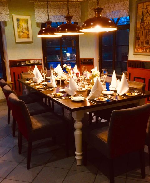 Ein schön dekorierter Tisch in einem Restaurant, gedeckt für mehrere Gäste. Die Atmosphäre ist warm und einladend mit sanfter Beleuchtung.