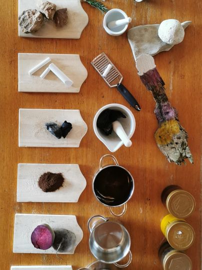 Eine Sammlung von verschiedenen Zutaten und Utensilien auf einer Holzplatte. Die Gegenstände sind ordentlich angeordnet, darunter Pulver, Behälter und Werkzeuge.