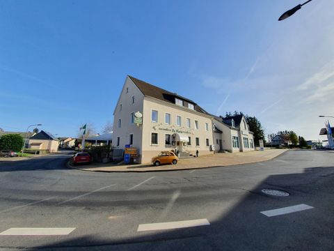 A modern building at a street corner with a clear sky in the background. Some cars are parked on the street.