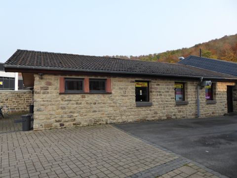 Ein kleines Steinhaus mit einem dunklen Dach. Es steht in einer ruhigen Umgebung, umgeben von Natur.