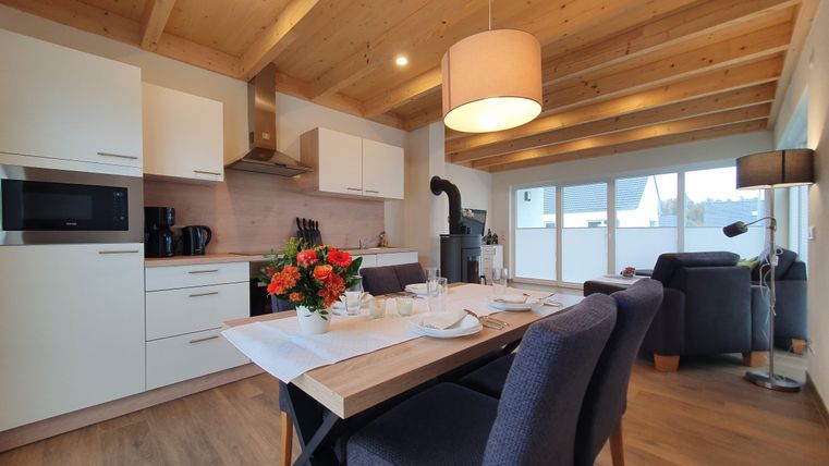 Eine moderne Küche mit einem Essbereich. Der Tisch ist gedeckt und Blumen stehen in der Mitte.