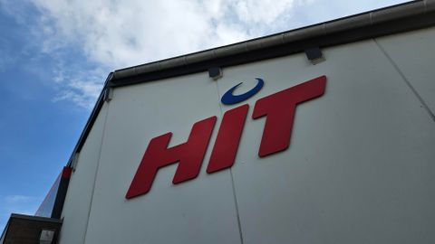 Ein Teil eines Gebäudes mit dem roten Logo "HIT". Der Himmel im Hintergrund ist teilweise bewölkt.