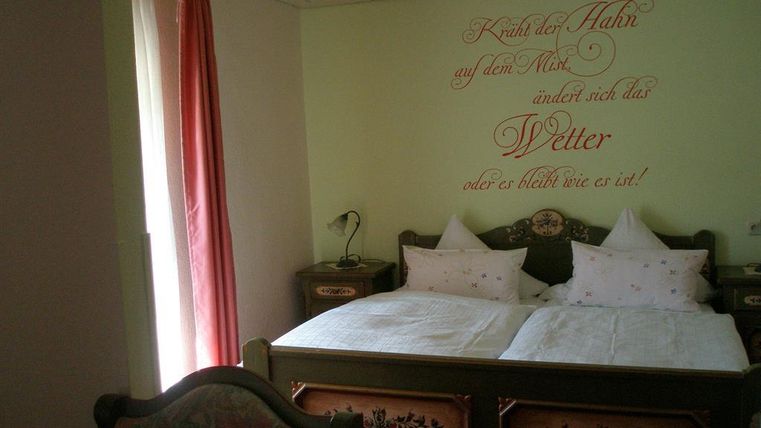 Ein gemütliches Schlafzimmer mit einem Doppelbett und bequemen Kissen. An der Wand steht ein inspirierender Spruch über das Wetter.