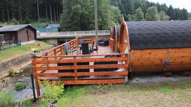Ein Holzhaus mit einer großen Terrasse und einem Blick auf die Natur. Umgeben von Bäumen und einer ruhigen Umgebung.