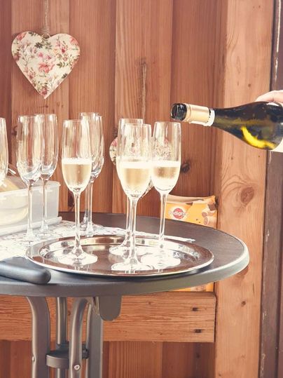 Eine Auswahl von Sektgläsern auf einem Tisch. Eine Hand schenkt Sekt in ein Glas.