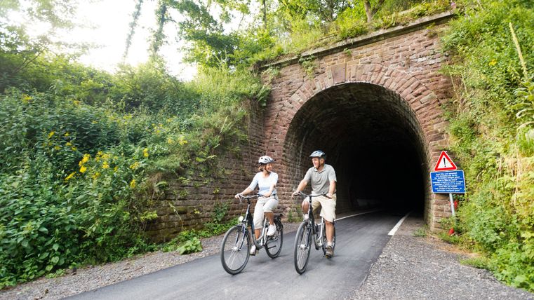 Zwei Radfahrer fahren aus einem Tunnel auf der Vennbahn bei Lommersweiler.
