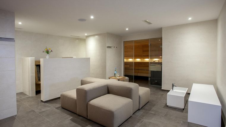 Ein modernes Wohnzimmer mit einem beigen Sofa und einem hellen, minimalistischen Design. Die Wände sind hell, und die Beleuchtung ist angenehm.