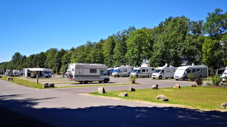 Ein ruhiger Campingplatz mit mehreren Wohnmobilen und viel grünem Raum. Die Atmosphäre ist friedlich und einladend.