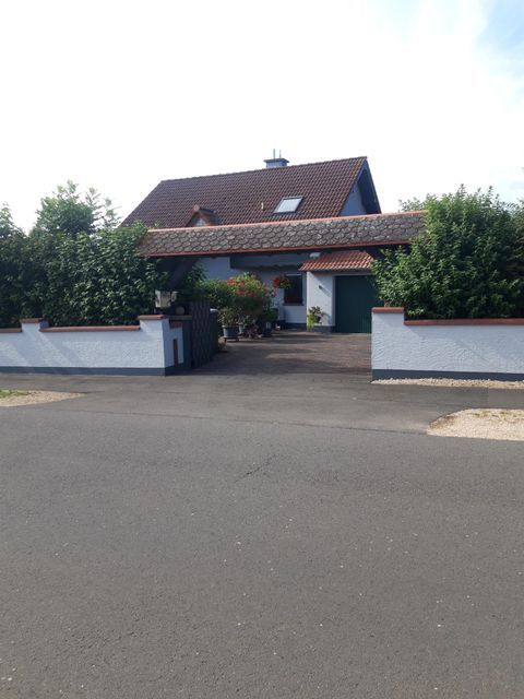 Ein schönes Haus mit einem Garten und grünen Hecken. Der Eingangsbereich ist gut sichtbar und freundlich gestaltet.