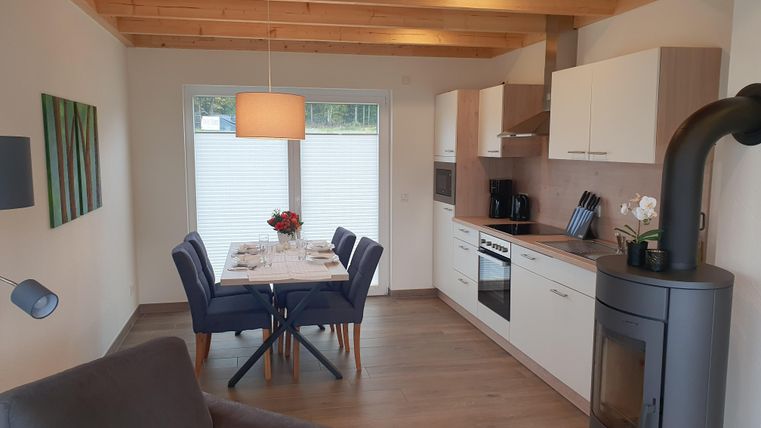 Eine moderne Küche mit Essbereich und gemütlichem Wohnraum. Große Fenster sorgen für viel Licht und einen offenen, einladenden Raum.