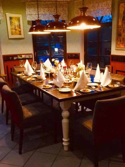 Ein elegant gedeckter Tisch in einem Restaurant mit Tischtüchern und Kerzen. Die Atmosphäre ist warm und einladend, ideal für ein gemütliches Essen.