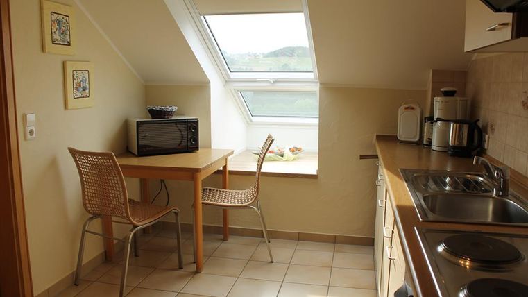 Eine einfache Küche mit einem Tisch und zwei Stühlen. Ein Fenster lässt viel Tageslicht herein und bietet eine schöne Aussicht.