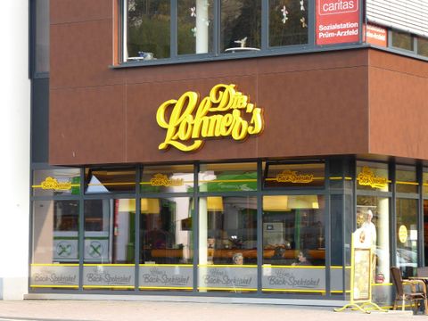 Ein Geschäft namens "Löhner's" mit gelbem Schriftzug an der Fassade. Die Fenster sind einladend gestaltet und zeigen verschiedene Produkte.